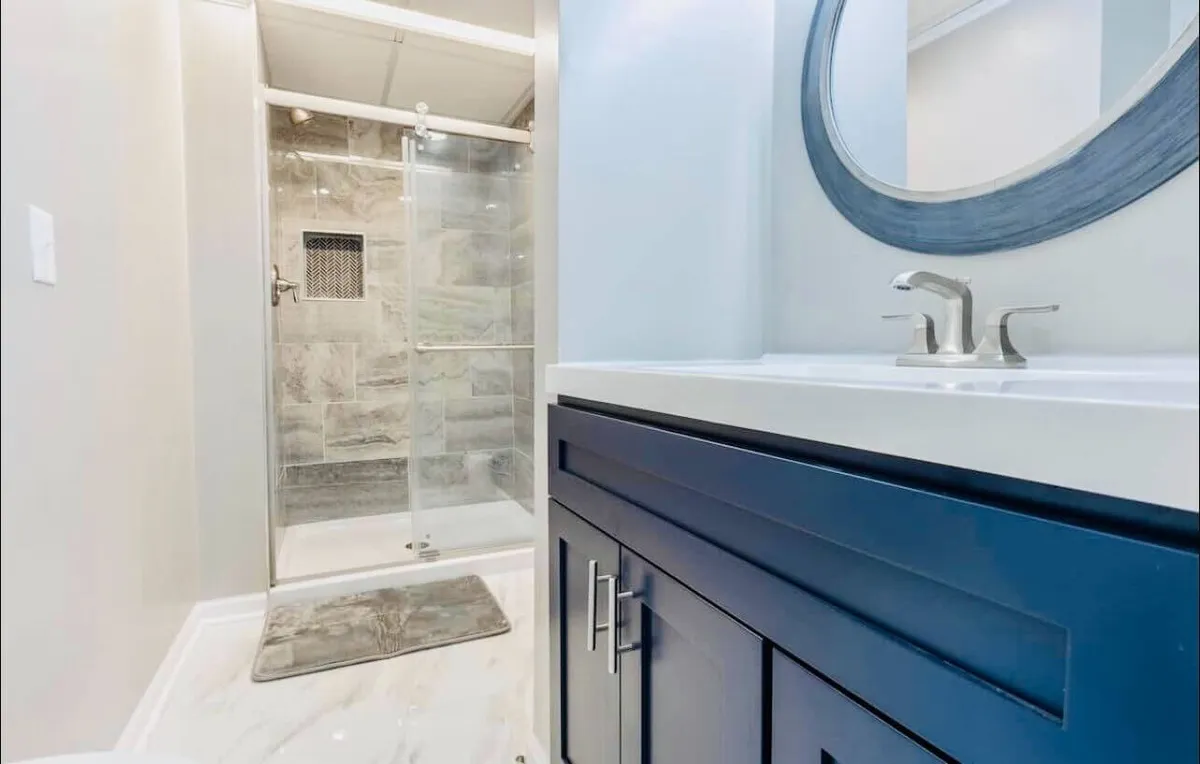 A modern bathroom scene centered on a spacious shower area, a sleek vanity sink, and a large mirror. The space is bright and inviting, with clean lines and fresh linens, evoking a sense of relaxation and privacy.