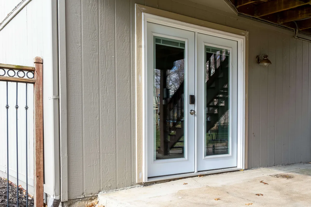 This image presents a double door entrance leading into the property, with a staircase and decorative railing in the background. The setting is clearly distinct from a shared apartment complex, emphasizing privacy and a welcoming residential feel.