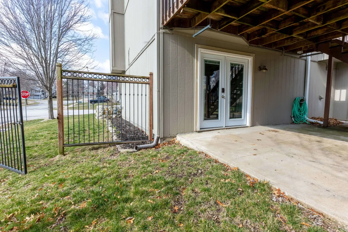 This image showcases the exterior of the basement apartment, featuring inviting double doors that open to a private, fenced patio space. The patio is arranged for outdoor dining or relaxing, framed by greenery and subtle landscaping, which enhances the sense of privacy and seclusion.